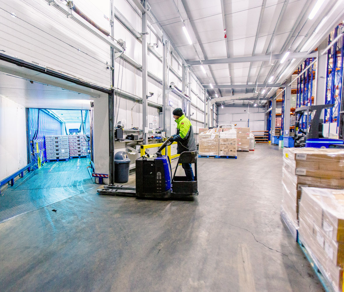 Hi-vis worker in a cold storage facility riding a forklift