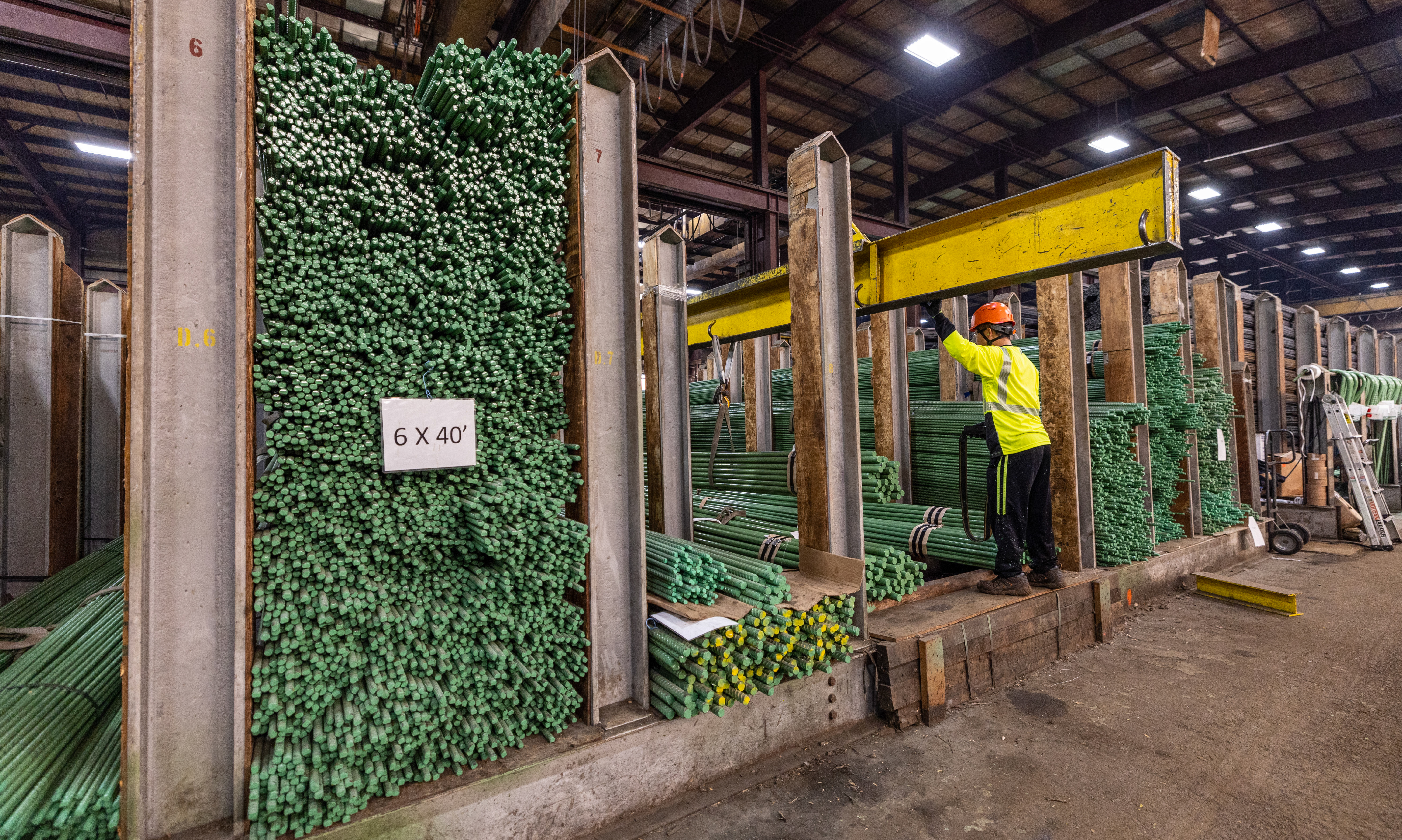 Worker wearing a hat hat in a warehouse surrounded by steel rod assortments