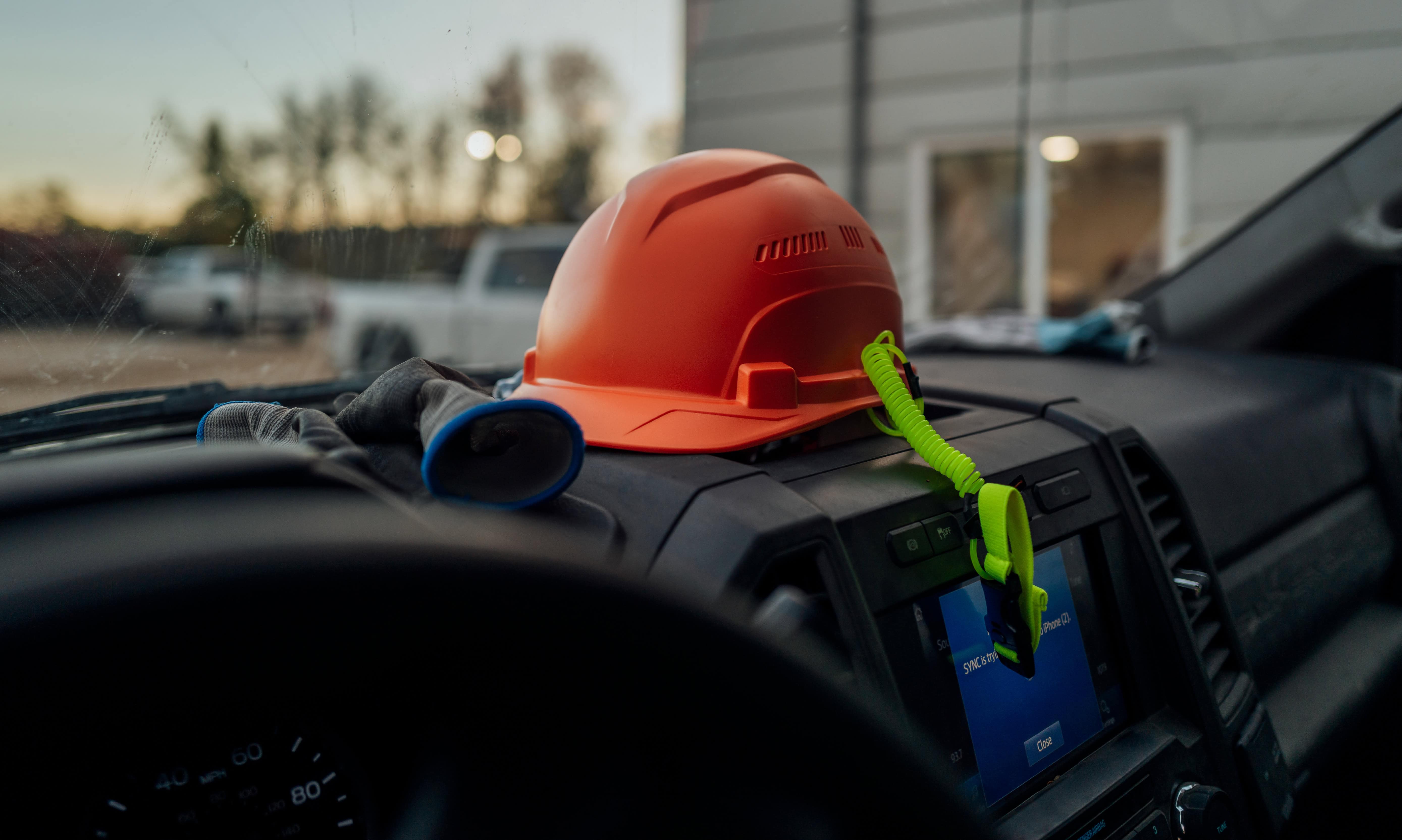 orange hard hat on the dashboard of a work truck