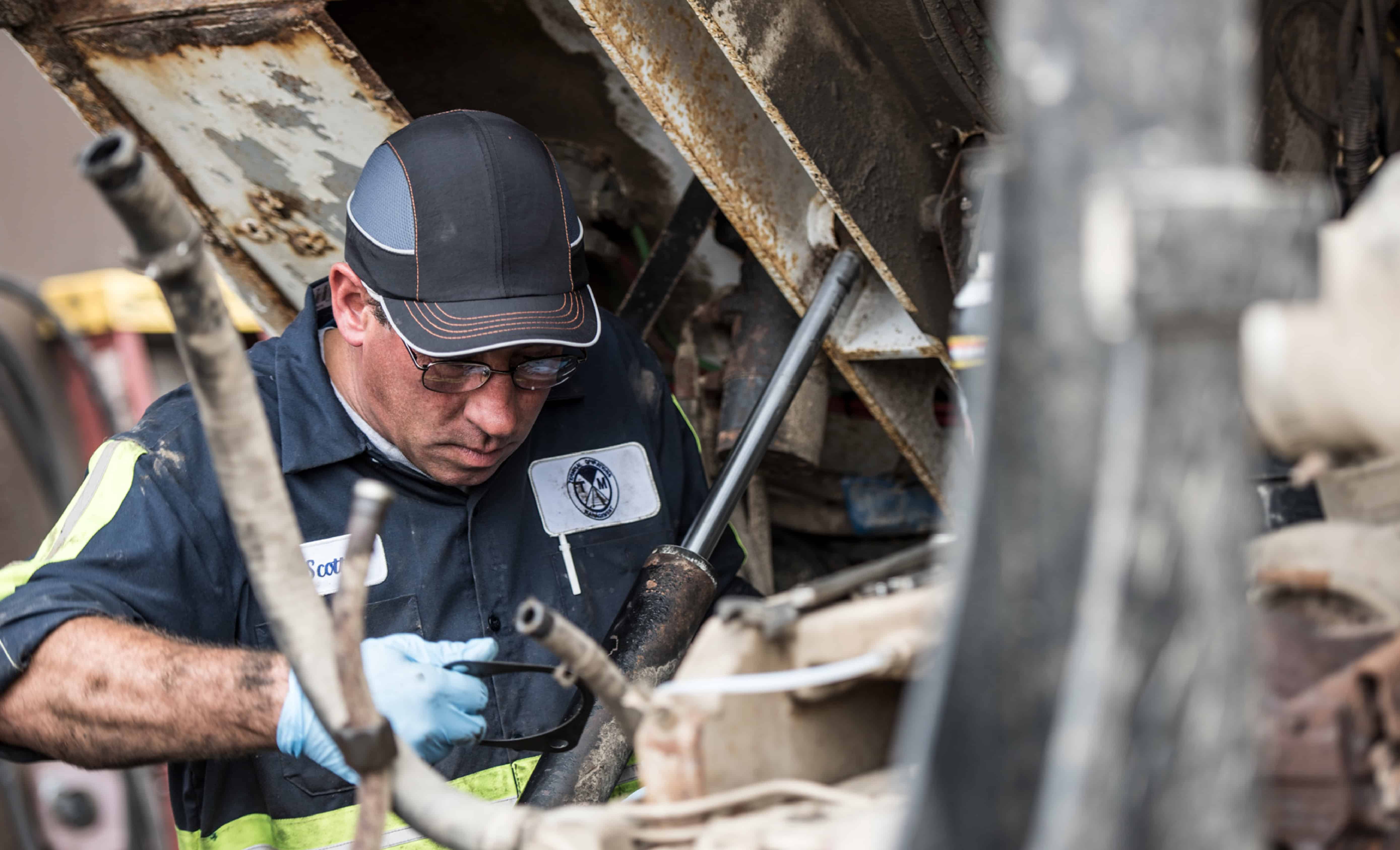 Worker in a tight space wearing a bump cap hat while inspecting machinery