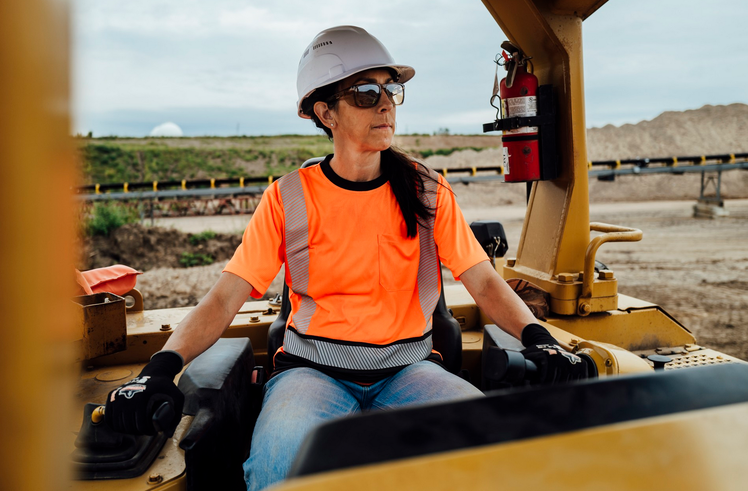 Woman wearing orange hi-vis t-shirt on a steamroller