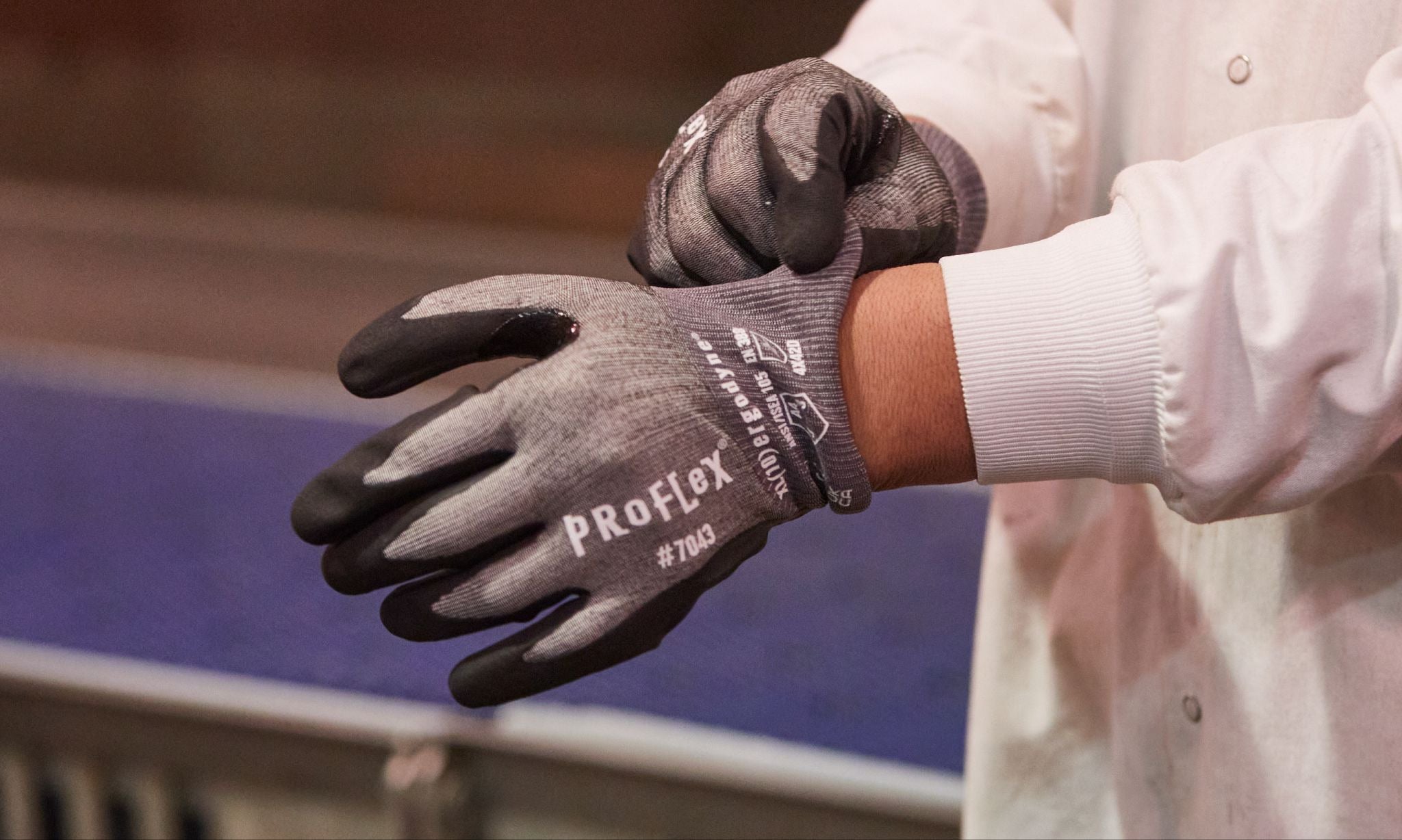 Worker putting on a pair of gray cut resistant gloves