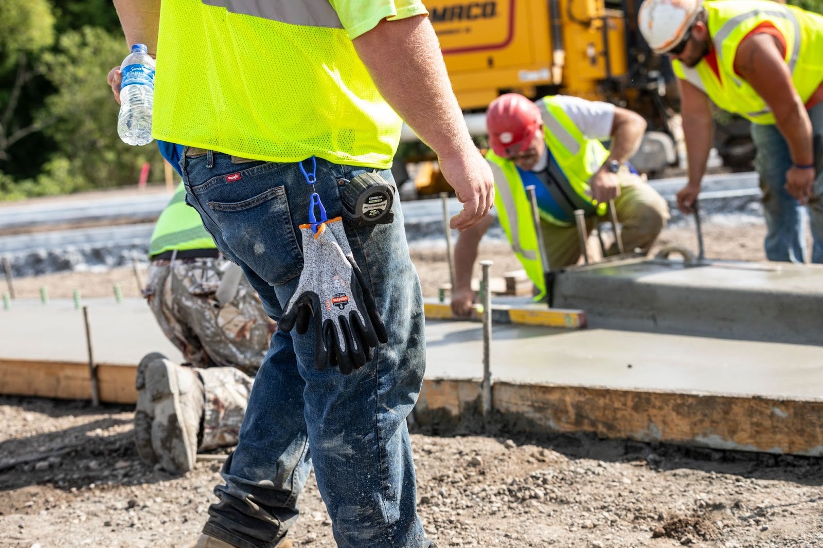 Worker on the jobsite with blue glove clip holding a pair of gloves attached to belt