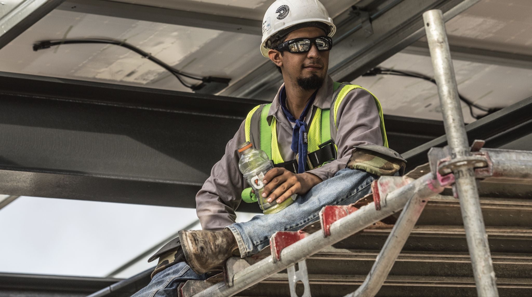 Worker taking a break while hydrating on scaffolding