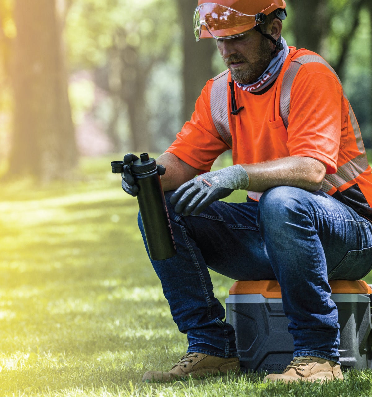 Worker sitting on a cooler while hydrating