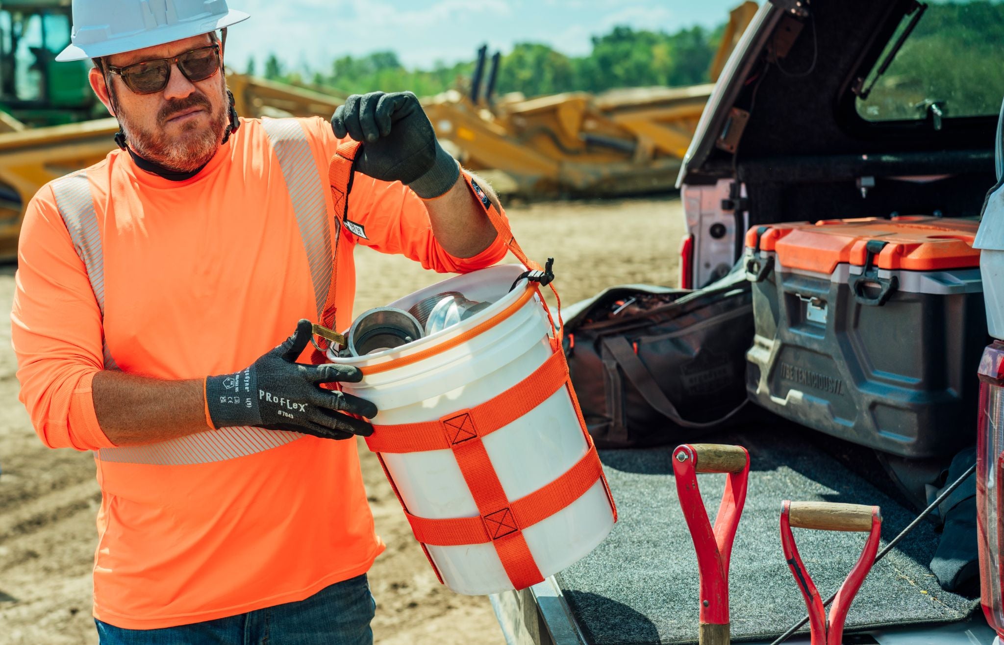 Worker using 5-gallon bucket carrier to carry parts