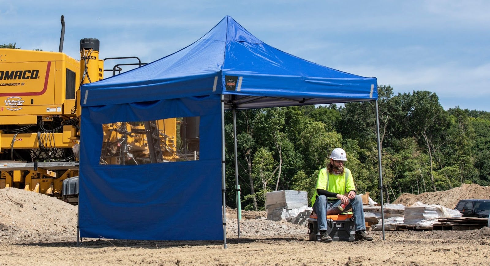 Worker taking a break underneath a blue pop-up tent