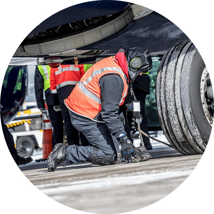 Airline worker kneeling under airplane wheel