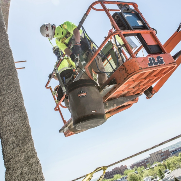 Construction workers using hoist bucket at heights to hold tethered tools