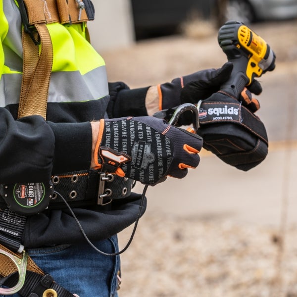 Worker attaching lanyard to attachment point on power drill