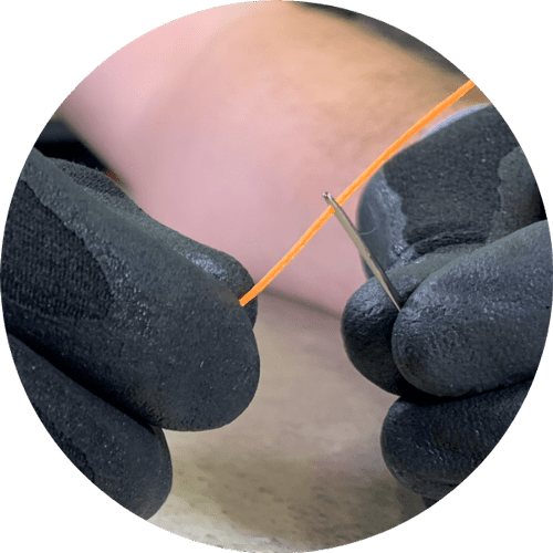 Gloved hand threading a needle