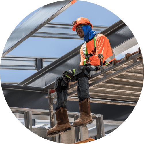 A worker sitting on scaffolding and taking a break on a hot day.