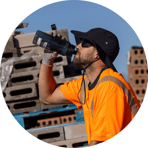 A worker drinking water from a Chill-Its 5151 Water Bottle and wearing a Chill-Its 8939 Cooling Bucket Hat