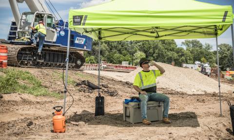 Worker drinking water under tent