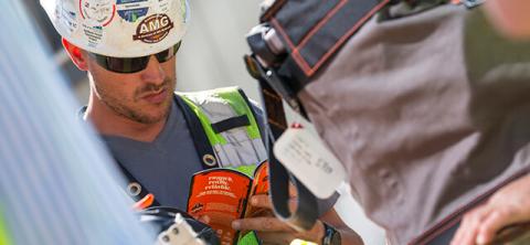 Worker in safety gear reading a pamphlet with hard hat on