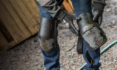 Worker strapping on Ergodyne hinged knee pads