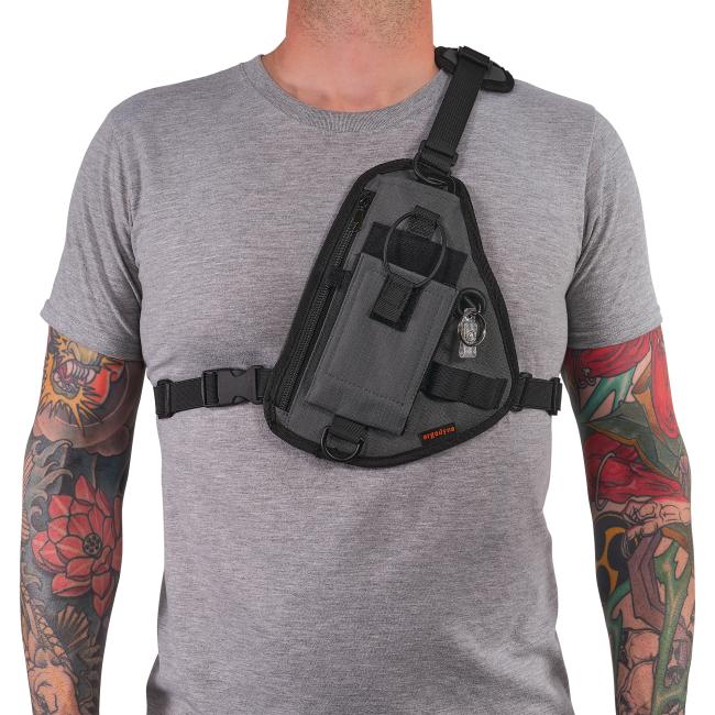 Torso of person in gray T-shirt wearing a dark gray crossbody sling bag across chest, tattooed arms visible