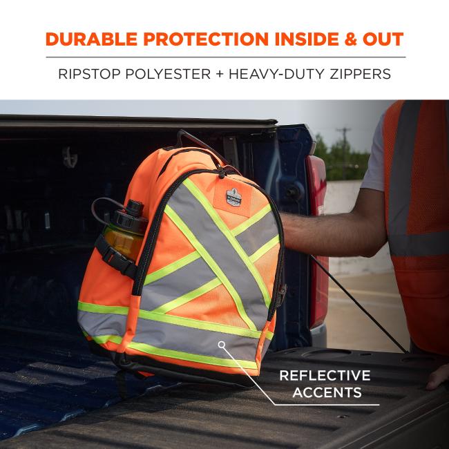 Bright orange high-visibility backpack with gray reflective and neon-yellow X accents in a pickup truck bed, partial person in orange safety vest.