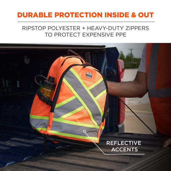 Orange high-visibility backpack with reflective gray and neon-yellow X accents in a pickup truck bed, worker's arm in an orange safety vest visible.