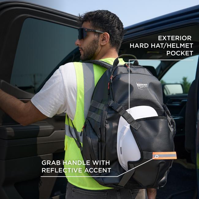 Man wearing sunglasses and neon safety vest with a dark backpack that has a white hard hat attached, standing by an open vehicle door.
