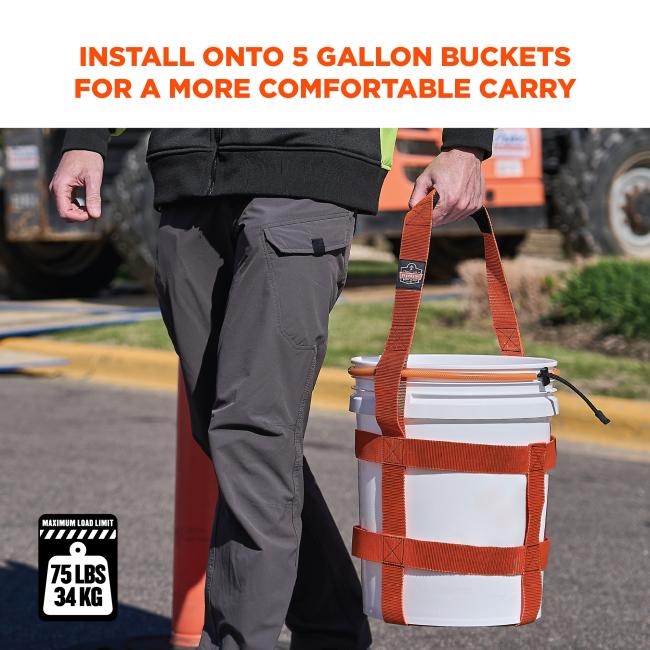Person's lower torso and hand holding orange webbing harness attached to a white plastic bucket