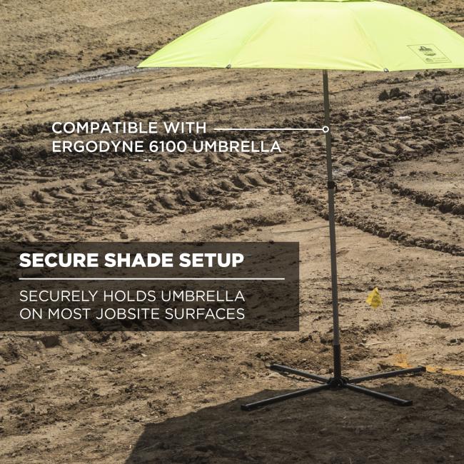 Lime-green umbrella canopy on a metal pole with cross-shaped base set on rough dirt, white text overlay visible