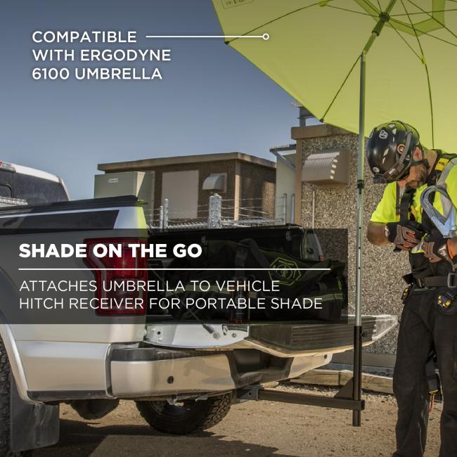 Open pickup tailgate with hitch-mounted pole holding a lime-green umbrella; a helmeted worker in high-visibility gear adjusts equipment.
