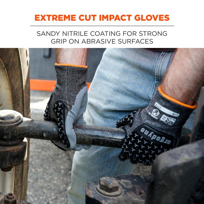 Close-up of two hands in gray textured gloves with orange trim gripping a rusted metal pipe, person wearing jeans