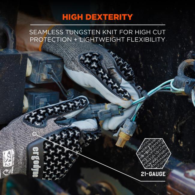 Close-up of gray knit work gloves with black textured grip pads holding electrical wires and connectors, with orange "HIGH DEXTERITY" text.