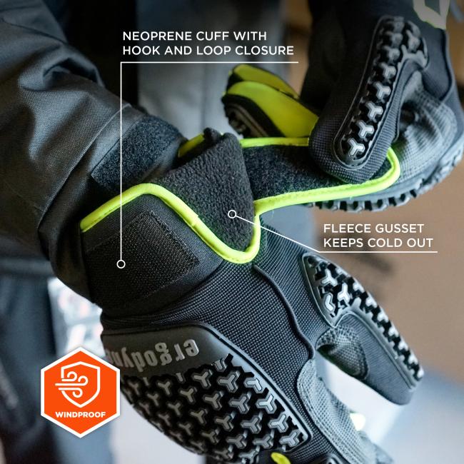 Close-up of a black glove with neon green trim, hook-and-loop cuff strap, fleece gusset and textured rubber grip/tread