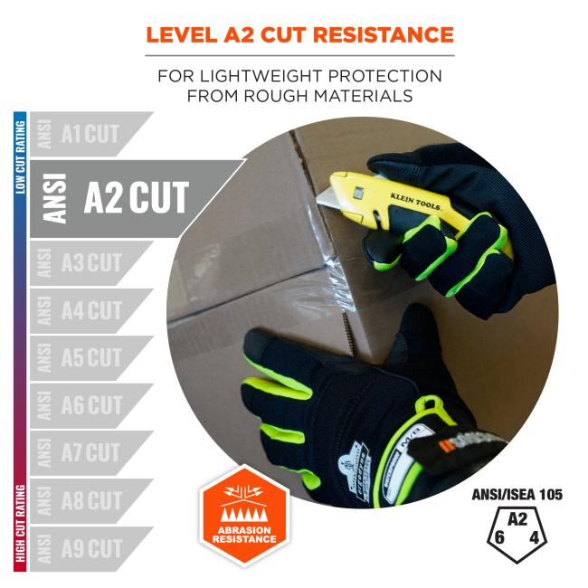 Black gloves with neon-green trim hold a yellow box cutter cutting cardboard; A2 cut resistance label and abrasion resistance icon shown.