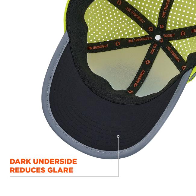 Close-up of cap interior: dark brim with gray edge, neon green polka-dot lining and black crossed inner straps with orange accents