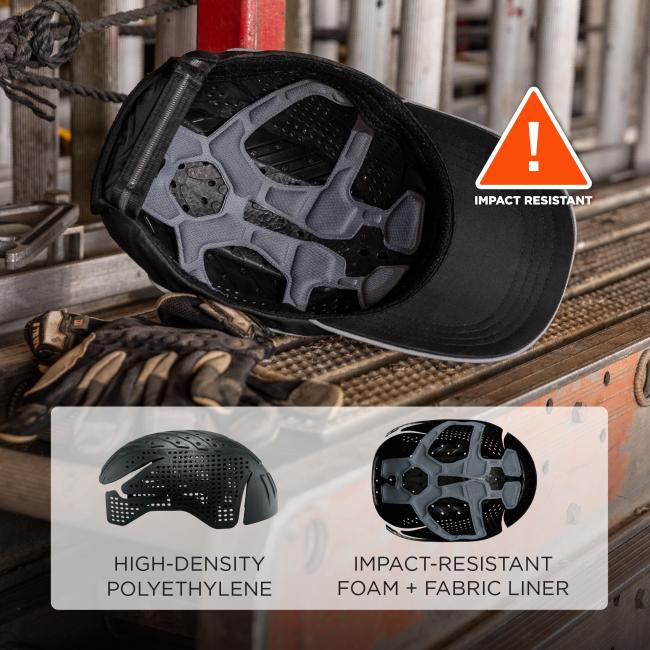 Black cap interior with grey padded impact foam liner on a metal workbench, worn gloves beside, orange triangle reading "IMPACT RESISTANT"