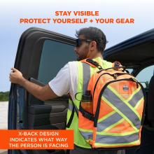 Man wearing sunglasses and neon safety vest carrying orange reflective backpack with X-pattern, opening a truck door.