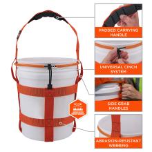 White plastic bucket with orange webbing harness, padded top handle, adjustable cinch cord and side grab straps.