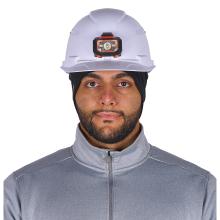 Close-up of person's face wearing a white hard hat with an orange-black headlamp, black head covering and gray zip-up jacket.