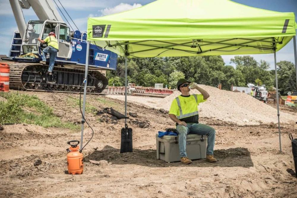 Worker resting and hydrating in the shade of a full tent