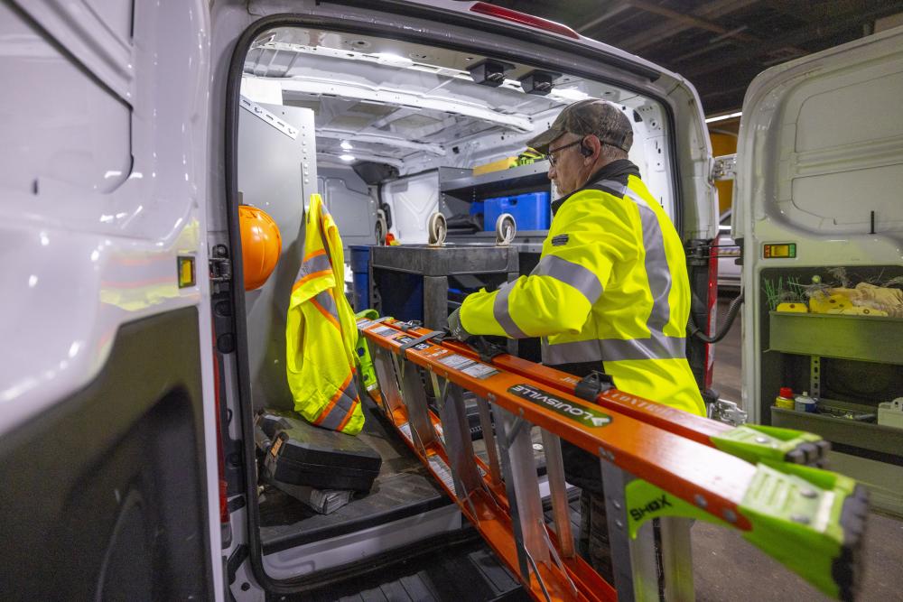 man putting a ladder into a van