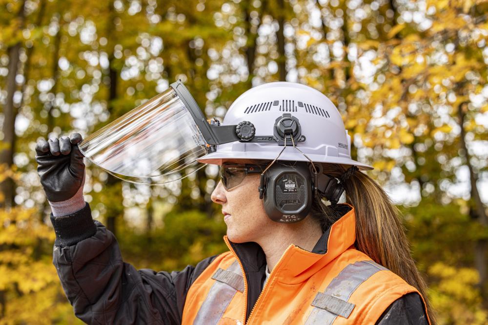 woman wearing hard hat, earmuffs and lifting up face shield