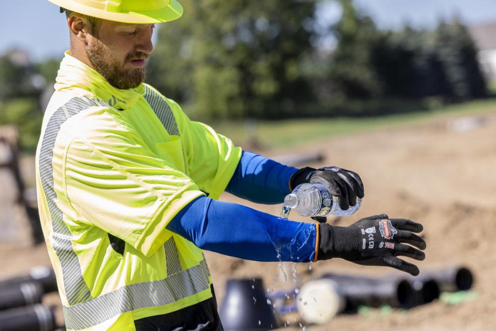 Man wearing a hard hat, hi-vis shirt and cooling arm sleeves.