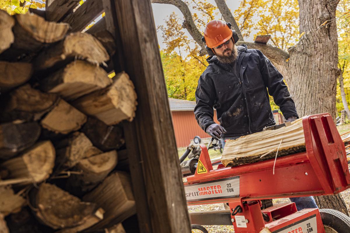 man wearing safety helmet and earmuffs cutting wood