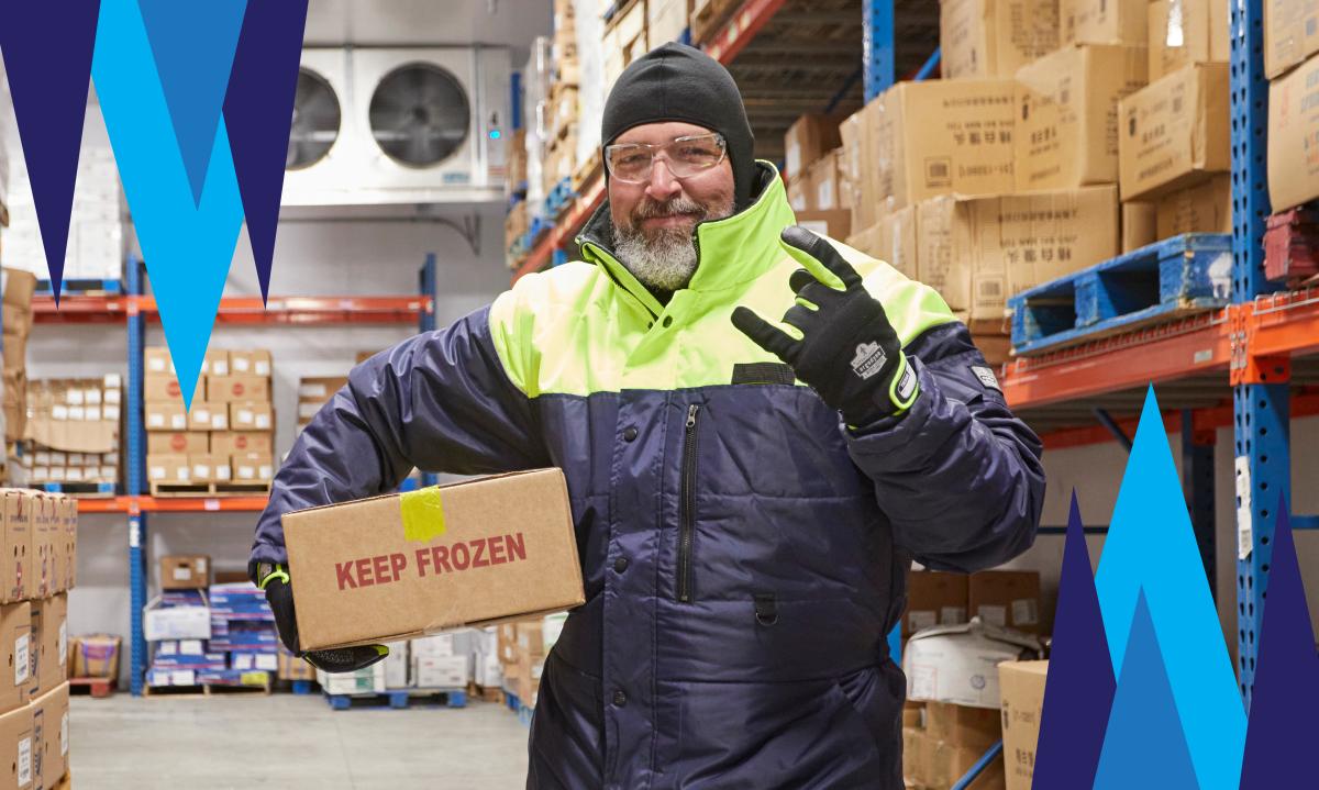 Worker in cold storage facility giving rock on hand sign while carrying a box