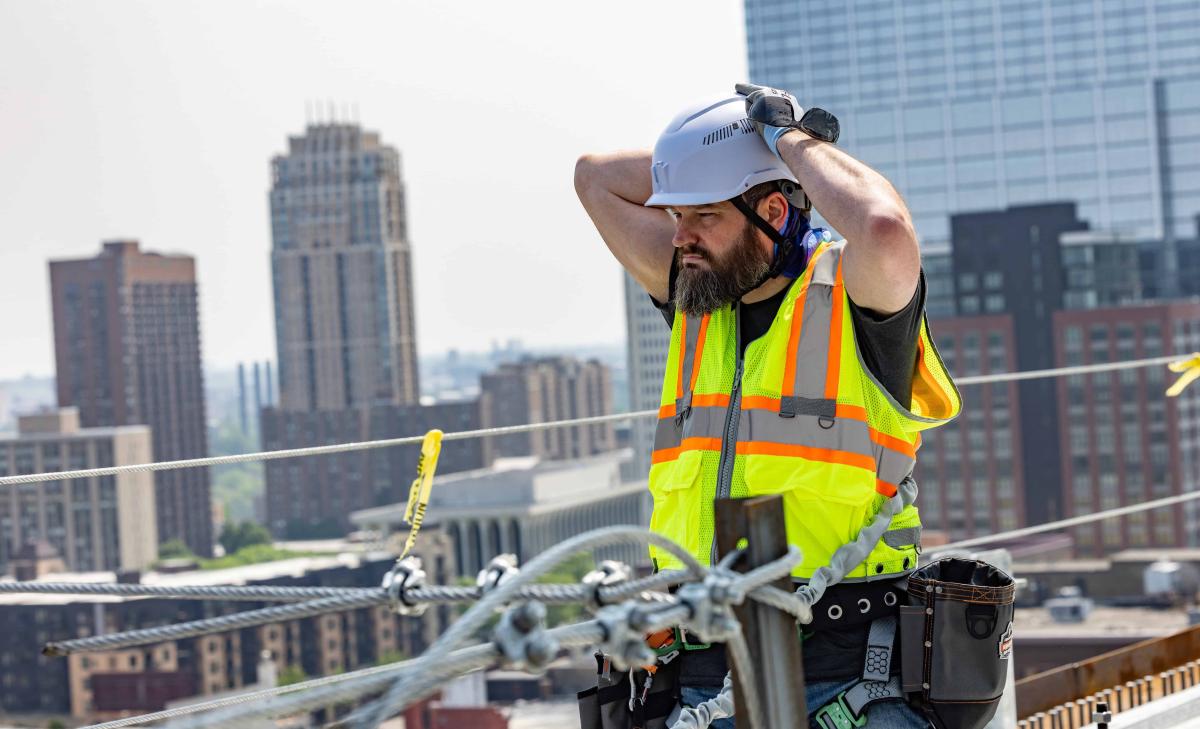 Worker wearing a hi-vis vest and a hard hat while working at heights