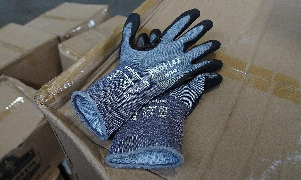 Pair of cut resistant gloves on a pile of cardboard packages