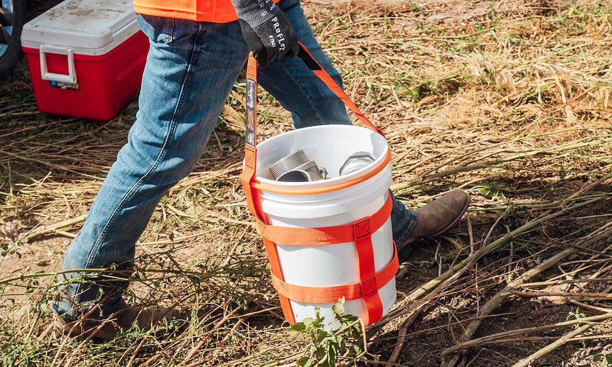Worker carrying a 5-gallon bucket in a bucket carrier