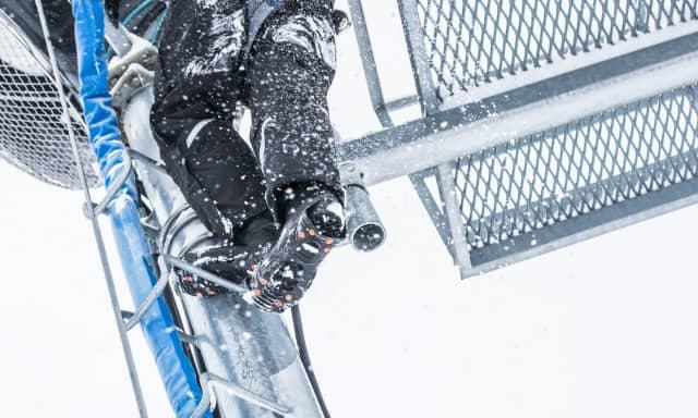 Worker climbing in winter with ice traction