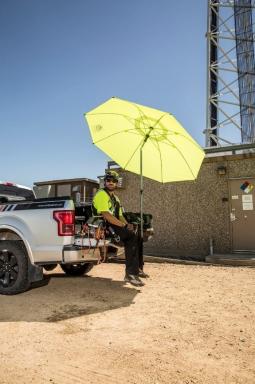 Worker being shaded by pop-up umbrella in a truck bed