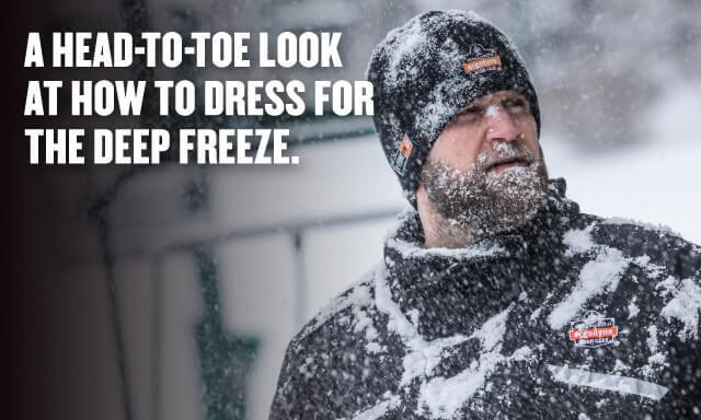 A head-to-toe look at how to dress for the deep freeze in text. Man in ergodyne winter gear during a blizzard